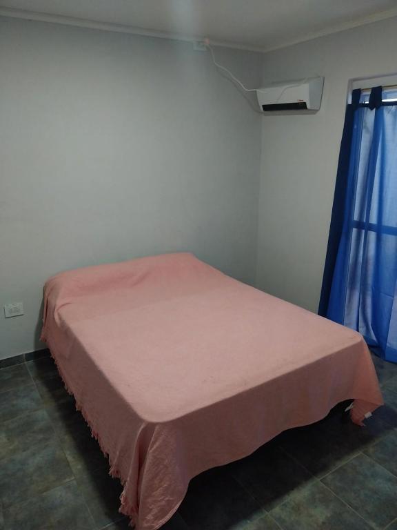 Una cama en una habitación con una manta rosa. en MAIPU Apart en Maipú