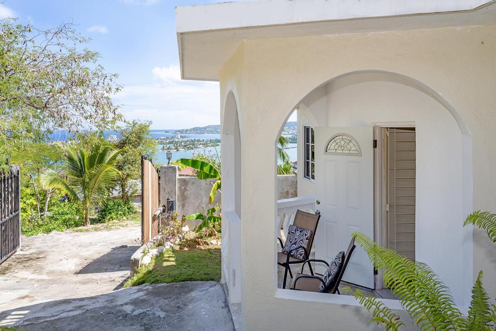 una casa blanca con un arco que conduce a una puerta en Palm Leaf Cottage, en Montego Bay