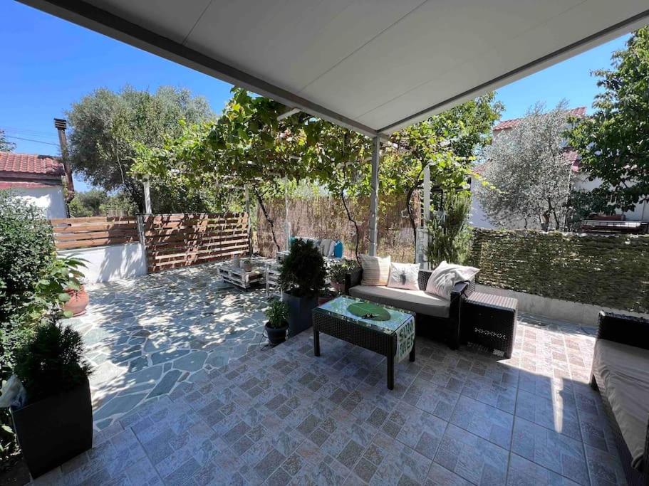un patio con un sofá bajo una sombrilla en Ευχάριστο εξοχικό σπίτι!, en AgiaKampos