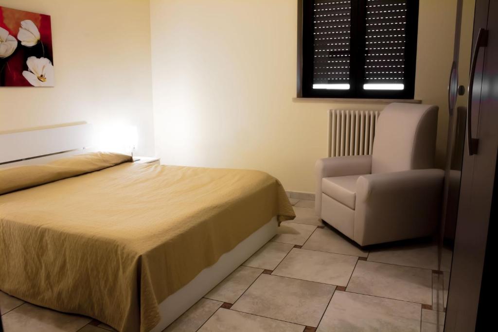 um quarto com uma cama e uma cadeira em Appartamento Ghalà em Galatone