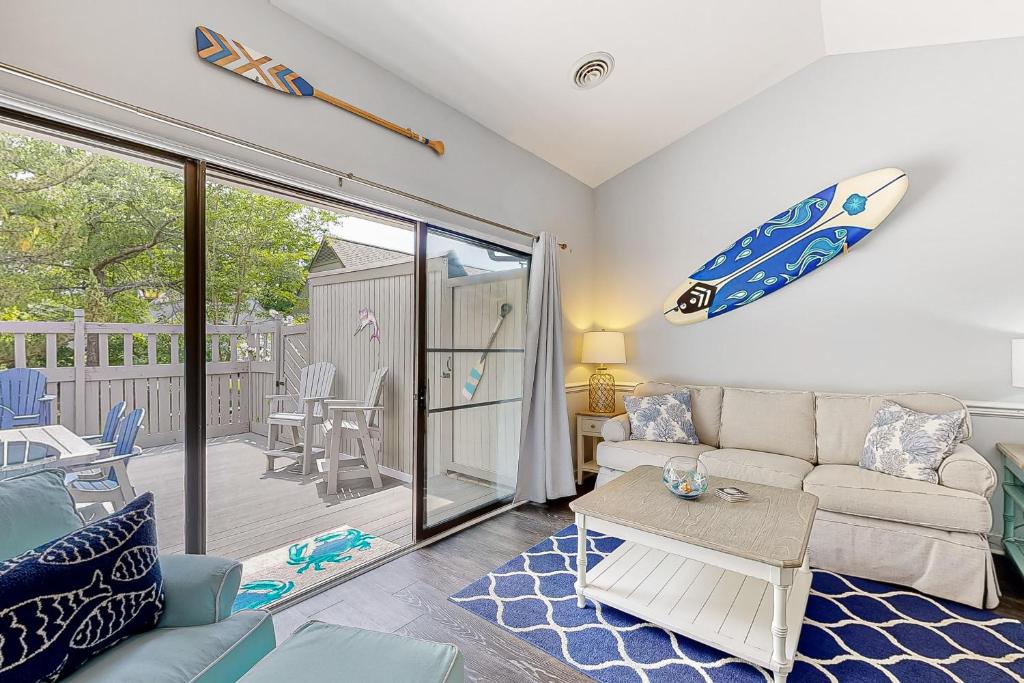 een woonkamer met een bank en een surfplank aan de muur bij Sea Colony --- 39353 W Pine Ct #1009C in Bethany Beach