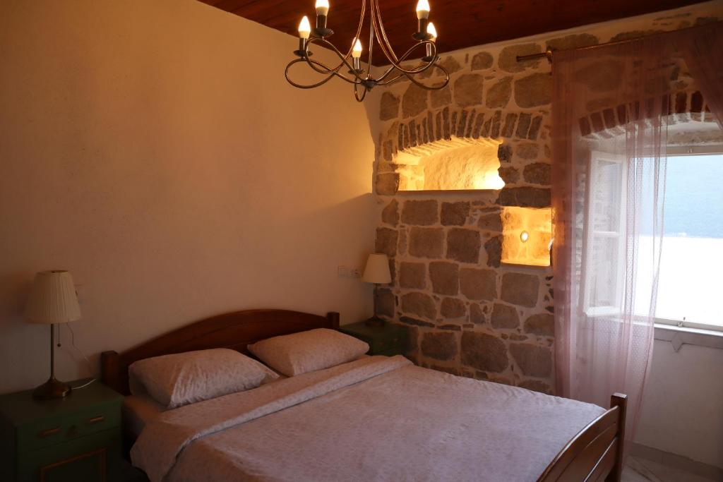 ein Schlafzimmer mit einem Bett und einer Steinmauer in der Unterkunft Guesthouse Žmukić in Perast