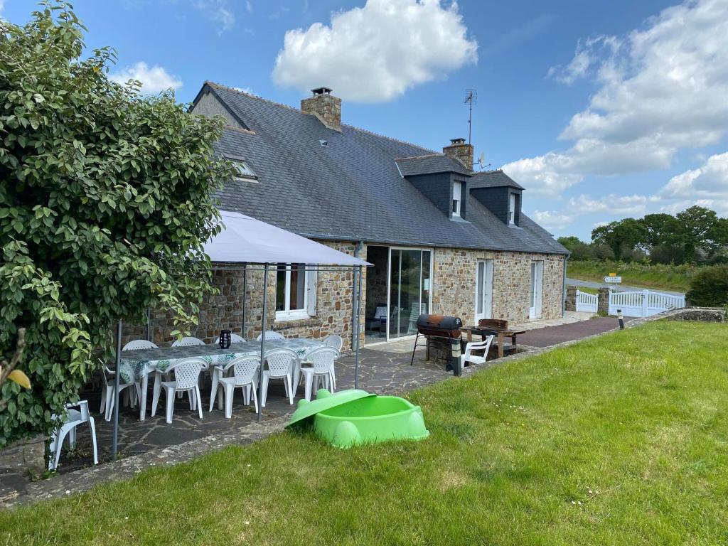 une maison avec une table et des chaises dans la cour dans l'établissement Country House near Barneville Coastline, à Saint-Maurice-en-Cotentin
