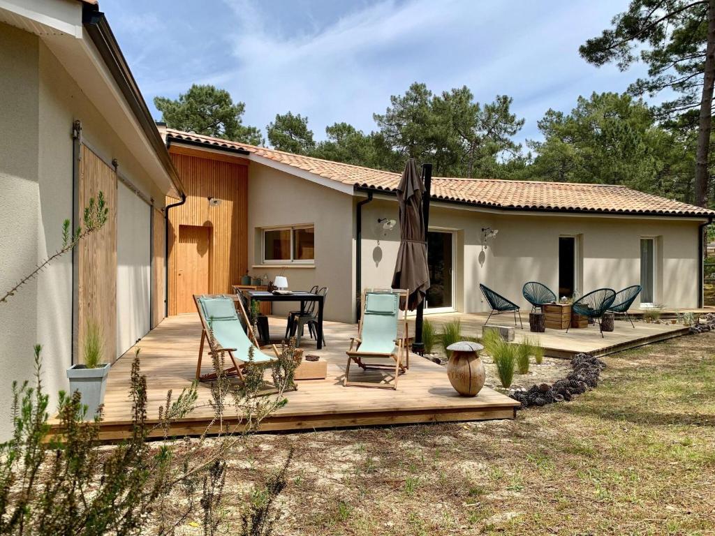 a deck with chairs and a table and a house at Detached holiday home with private garden in Carcans