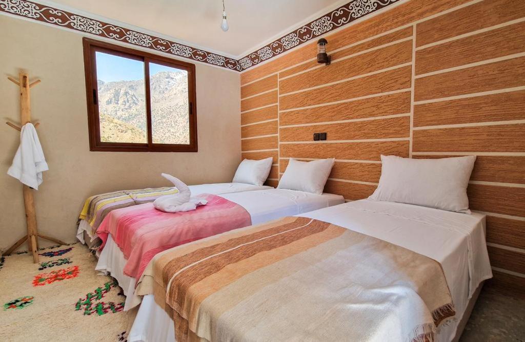 1 dormitorio con 2 camas y ventana en Toubkal Views en Imlil