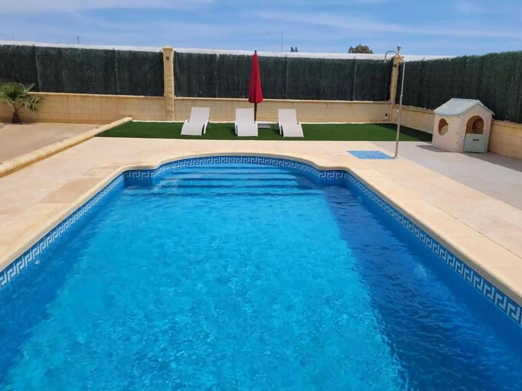 a swimming pool with two white chairs next to it at Belvilla by OYO Villa Valerya in Ibáñez