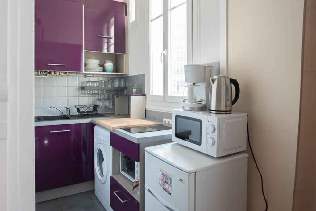 cocina con armarios morados y microondas en Warm and bright apartment of 30 m, en Boulogne-Billancourt