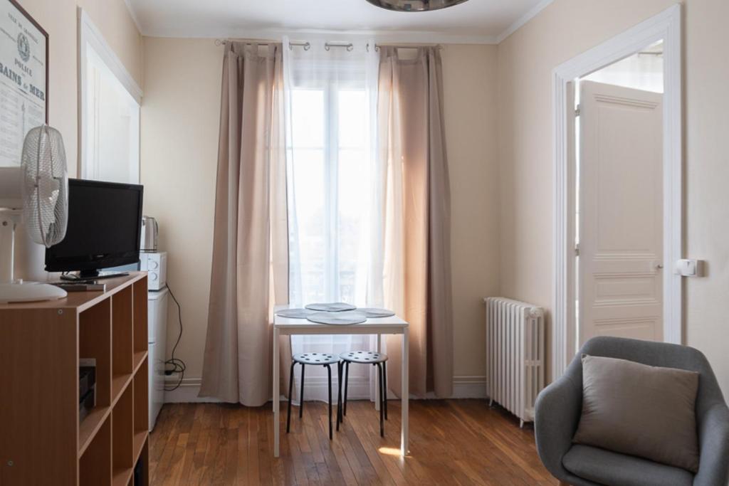 sala de estar con mesa, silla y TV en Warm and bright apartment of 30 m, en Boulogne-Billancourt