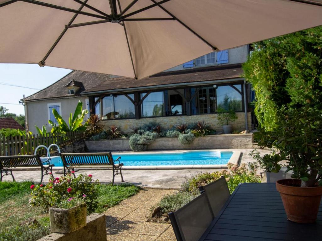 a house with an umbrella and a swimming pool at Gîte La Bachellerie, 4 pièces, 6 personnes - FR-1-616-294 in La Bachellerie