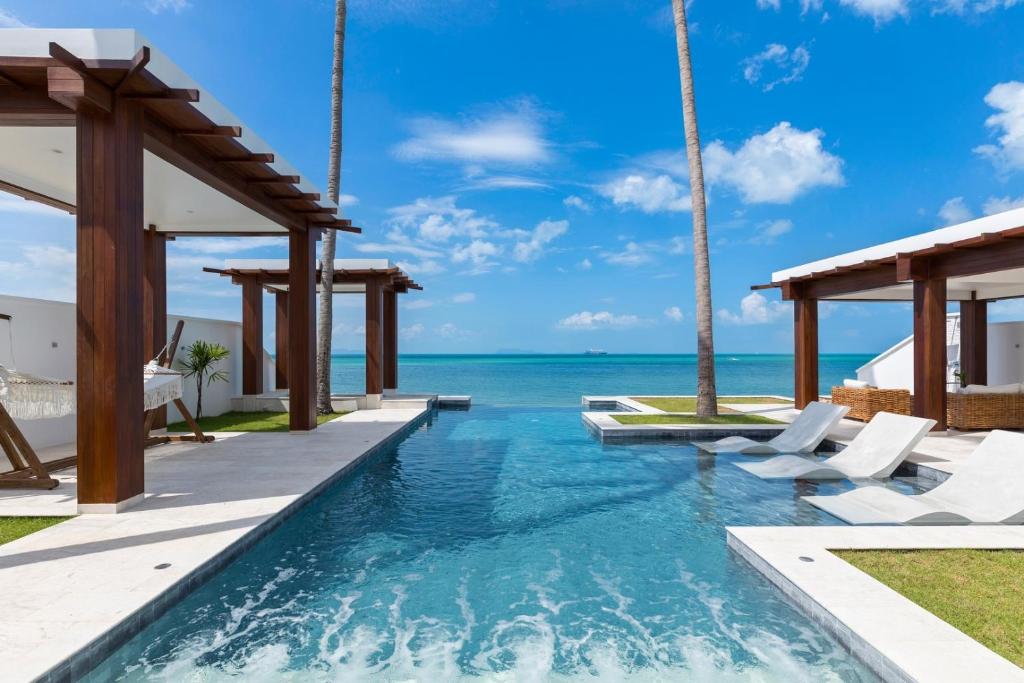 une piscine avec des chaises et l'océan en arrière-plan dans l'établissement Villa Hanna Luxury Beachfront Koh Samui, à Koh Samui 