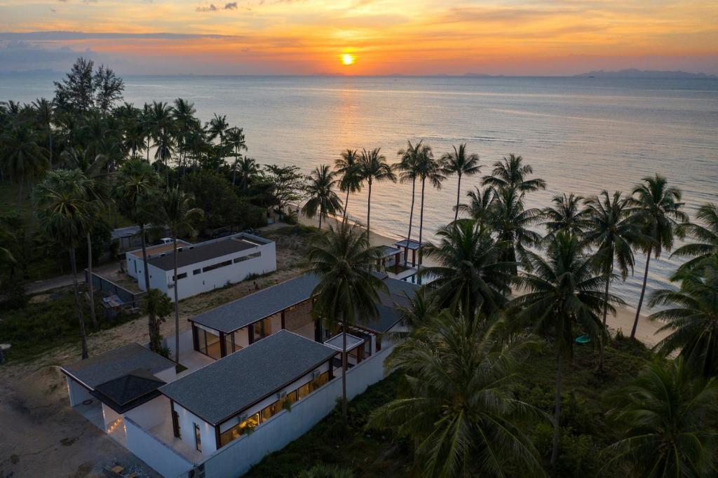 苏梅岛Villa Hanna Luxury Beachfront Koh Samui的日落时分海滩上度假村的空中景致