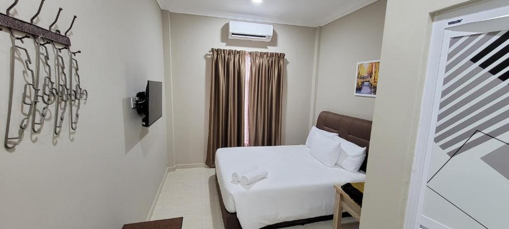 um quarto com uma cama branca e uma janela em HOTEL SHAFURA 3 em Cukai