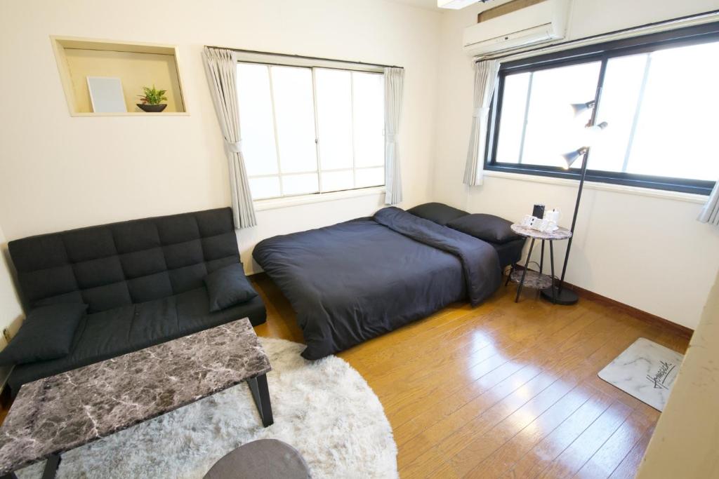 a bedroom with a bed and a couch and a chair at PLAZA IKEJIRI 201 in Tokyo