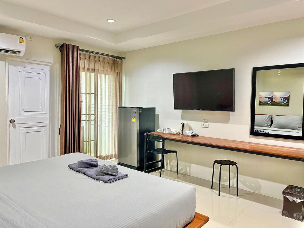 Cette chambre comprend un lit, un bureau et une télévision. dans l'établissement The Gun Hotel 8, à Surin
