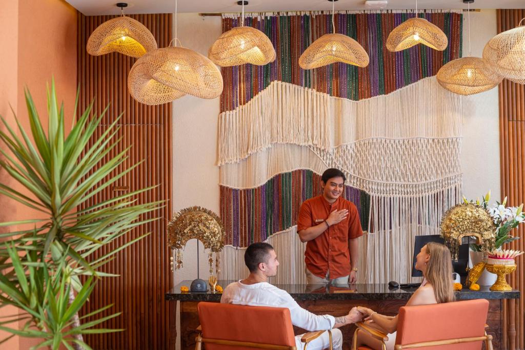Ein Mann und eine Frau sitzen auf Stühlen in einem Zimmer in der Unterkunft Cyrus Villa Seminyak by Ini Vie Hospitality in Seminyak