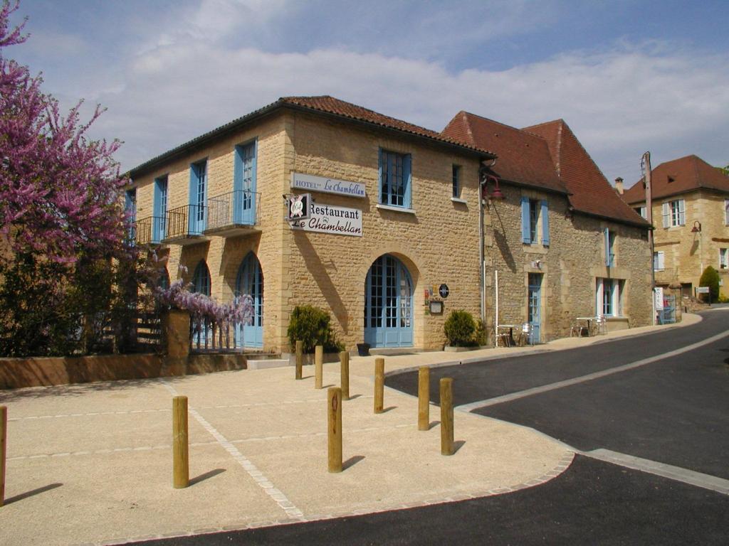 a building with a row of posts in front of a street at Le Chambellan in Coux-et-Bigaroque