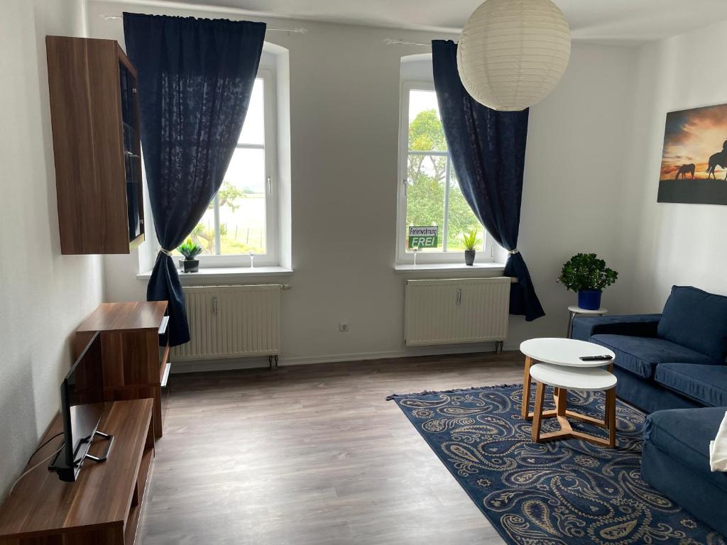 a living room with a blue couch and two windows at Ferienwohnung Nahe Schiffshebewerk 