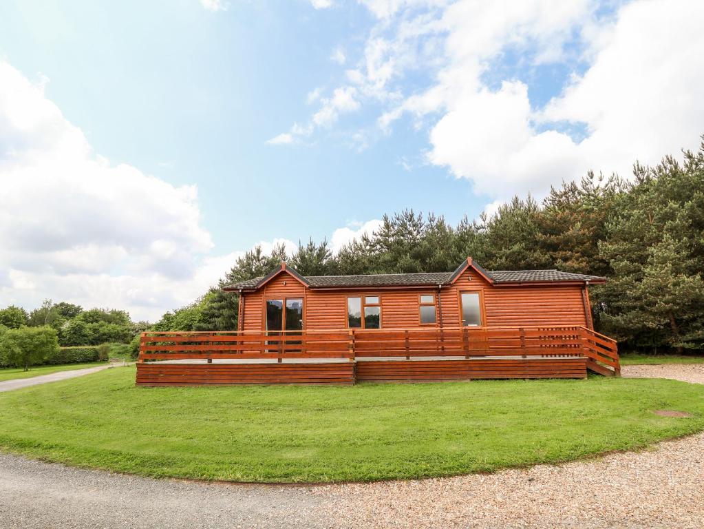 a wooden cabin on a grassy field with a house at Callow Lodge 5 in Hadnall
