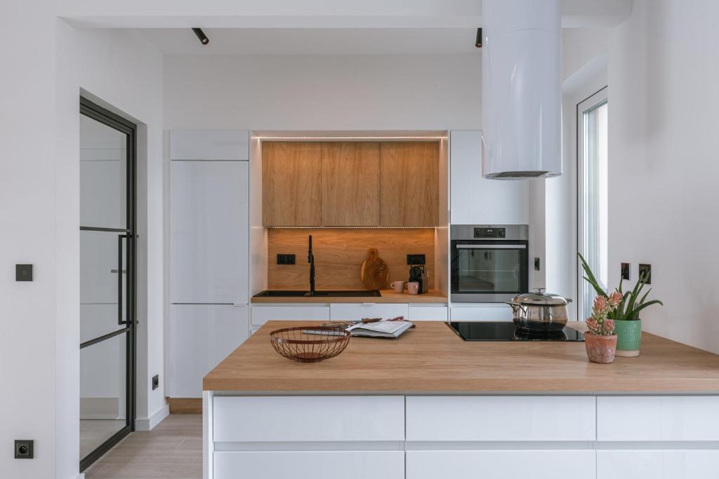 cocina con armarios blancos y encimera de madera en Beautiful modern holiday house with private garden, en Bredene