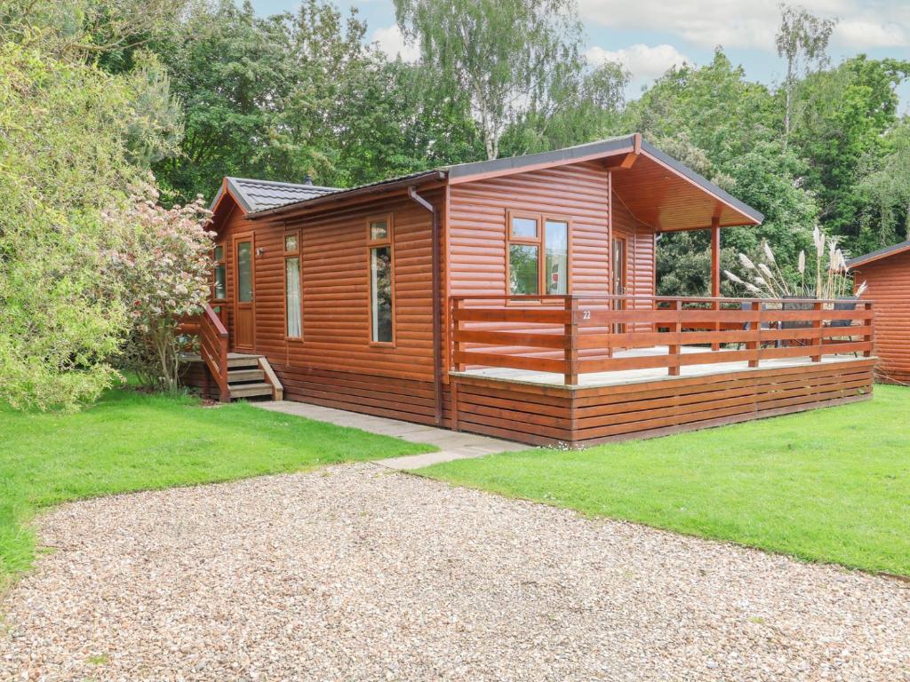 a log cabin with a porch and green grass at Callow Lodge 22 in Hadnall