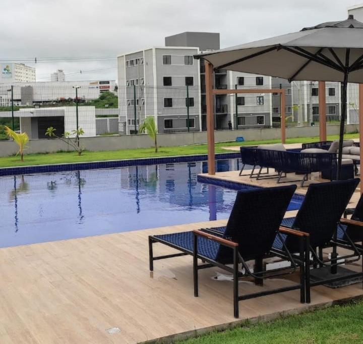 eine Terrasse mit Stühlen und Sonnenschirm und ein Pool in der Unterkunft Garden Ipojuca Caruaru in Caruaru