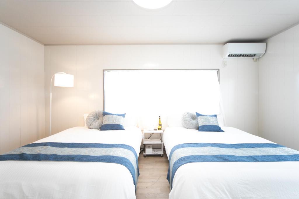two beds in a room with a window at Yokkaichi Kawaramachi Hotel in Hazu