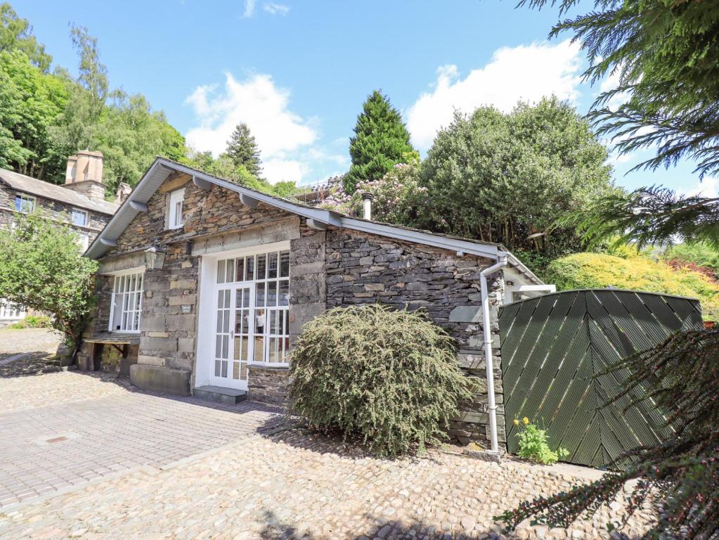 a stone house with a garage on a driveway at Courtyard Cottage in Ambleside