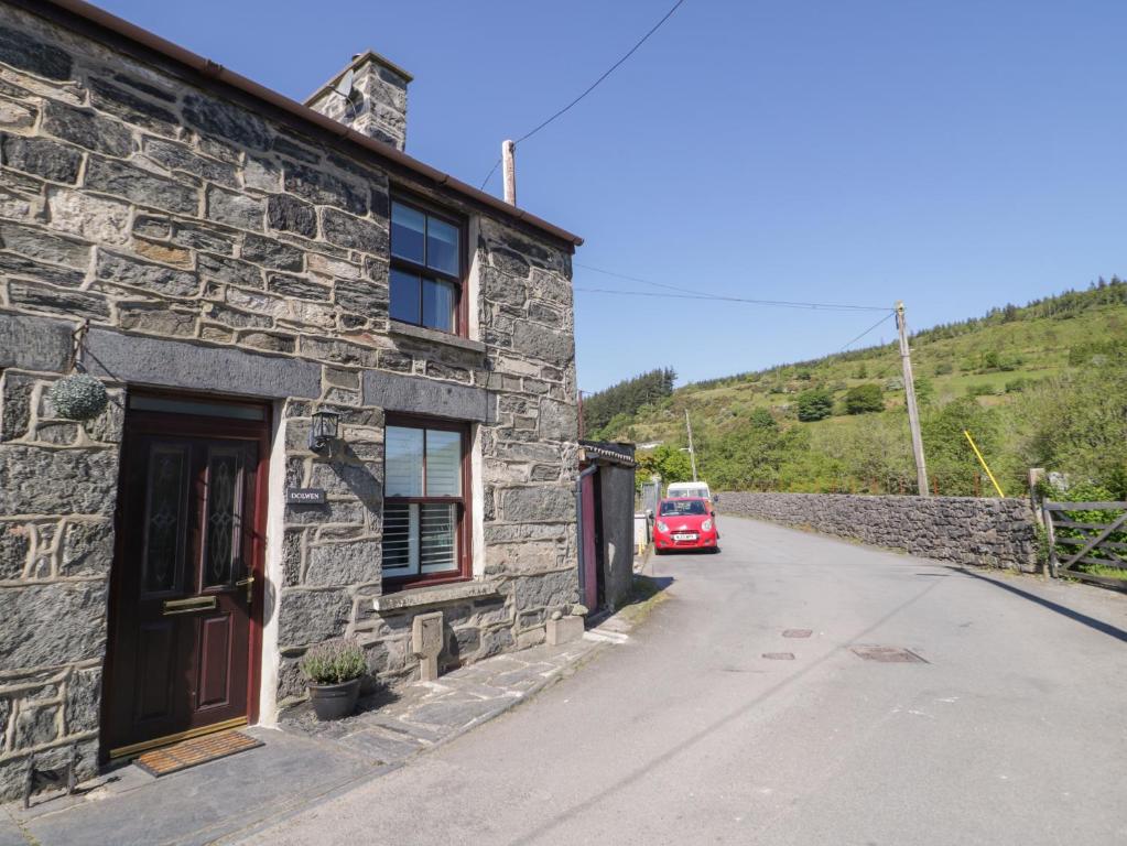 a red car parked next to a stone building at Dolwen in Betws-y-coed