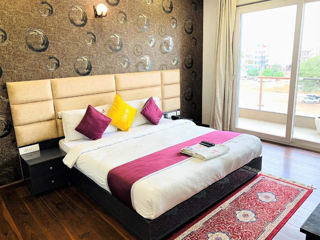 a bedroom with a large bed with purple and yellow pillows at Lime Tree Hotel Pulkit Gurgaon-Artemis Hospital, Nearest Metro Huda City Centre in Gurgaon