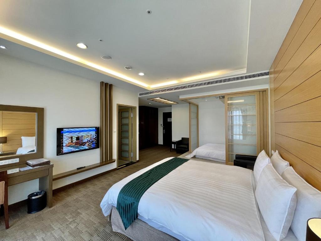 Habitación de hotel con cama, escritorio y TV. en Cheng Wan Grand Hotel en Puli