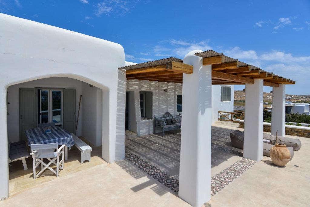 アノ・メラにあるMykonos 4 bedroom Cycladic home with free parkingのテーブル付きパティオが備わるホワイトハウスです。