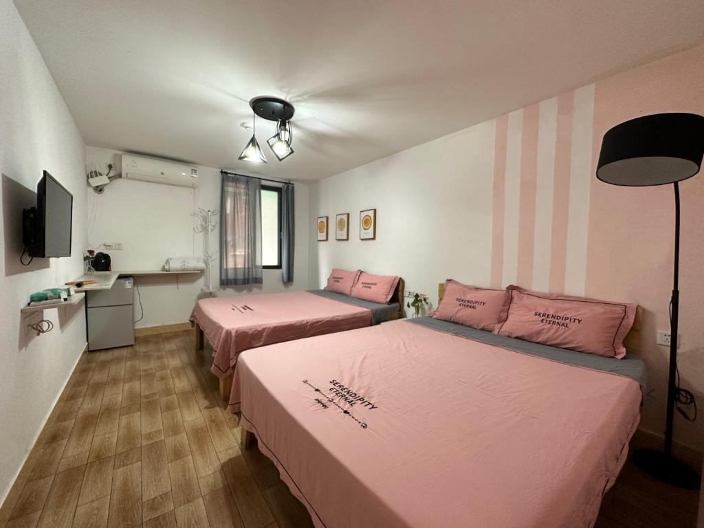 廣州的住宿－臨江公寓，配有粉红色床单的客房内的两张床