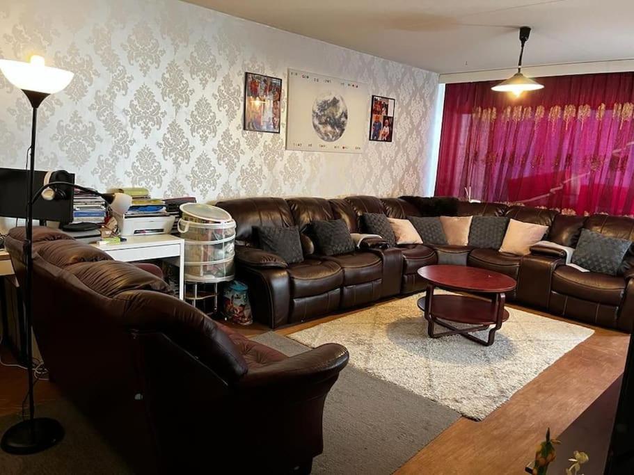 a living room with brown leather couches and a table at 2 Bedroom's 1 sitting room Majesty Palace in Espoo