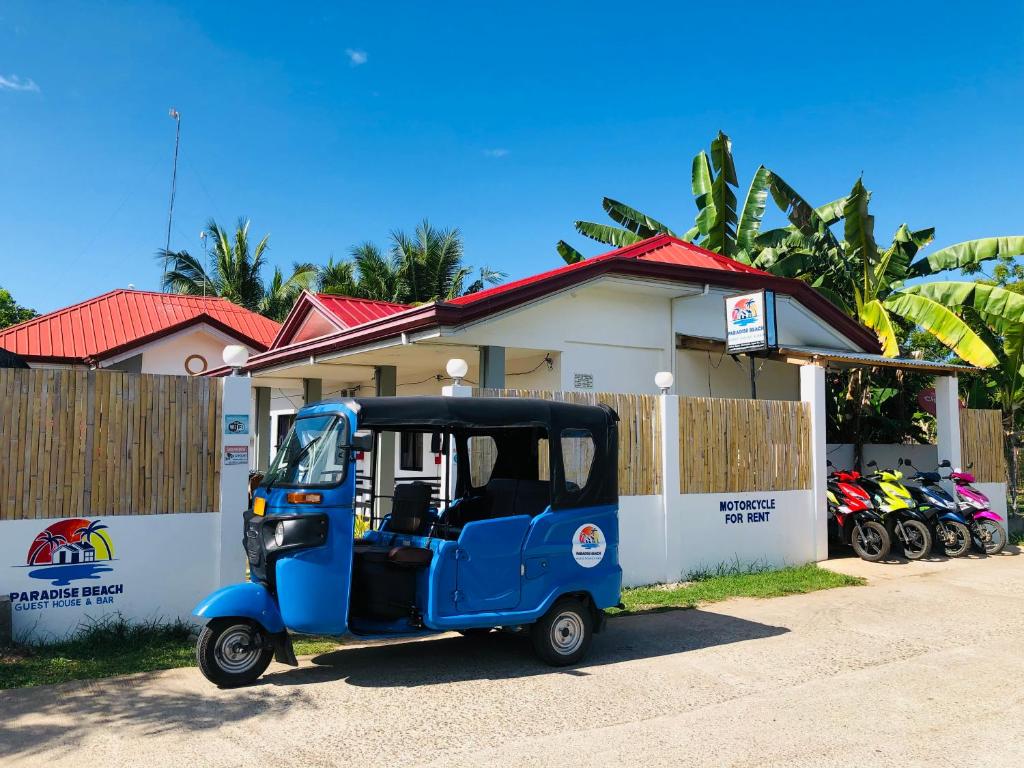 un piccolo golf cart blu parcheggiato di fronte a una casa di Paradise Beach Guest House a Isola di Bantayan