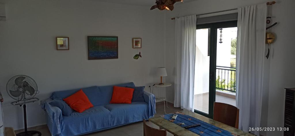 a living room with a blue couch and a window at Orange Tree Garden in Pefkochori