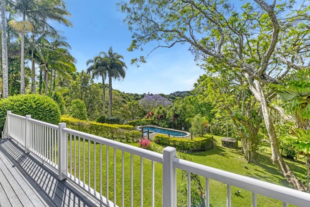 a wooden deck with a white fence and trees at Hinterland Luxury Stay - Eastnor in Montville