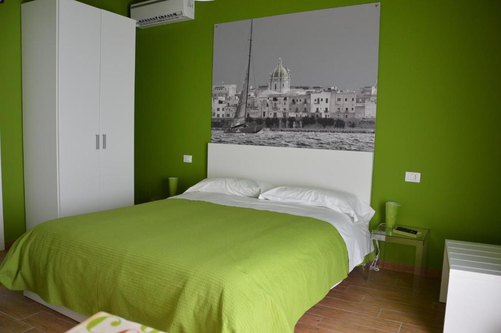 a green bedroom with a bed with a picture on the wall at Casa Magistrale in Trapani