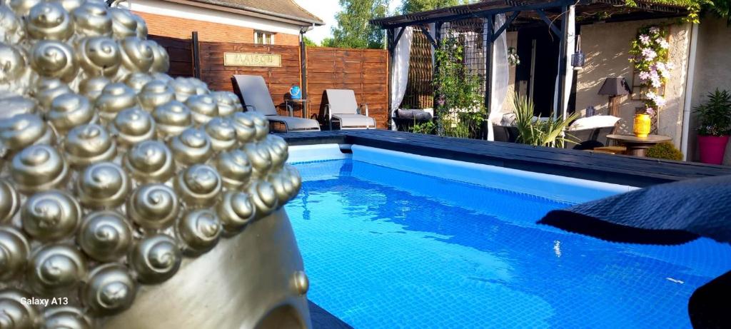 a swimming pool with blue water and silver spheres on it at Les Epinettes chambres d'hôtes in Crèvecoeur-le-Grand