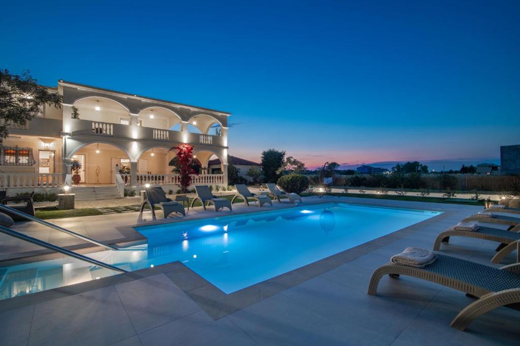 a swimming pool with chairs and a house at La Casa Di Nina in Laganas