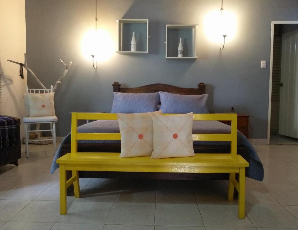 Habitación Casa Las Aves في هوندا: مقعد أصفر مع وسائد في غرفة النوم