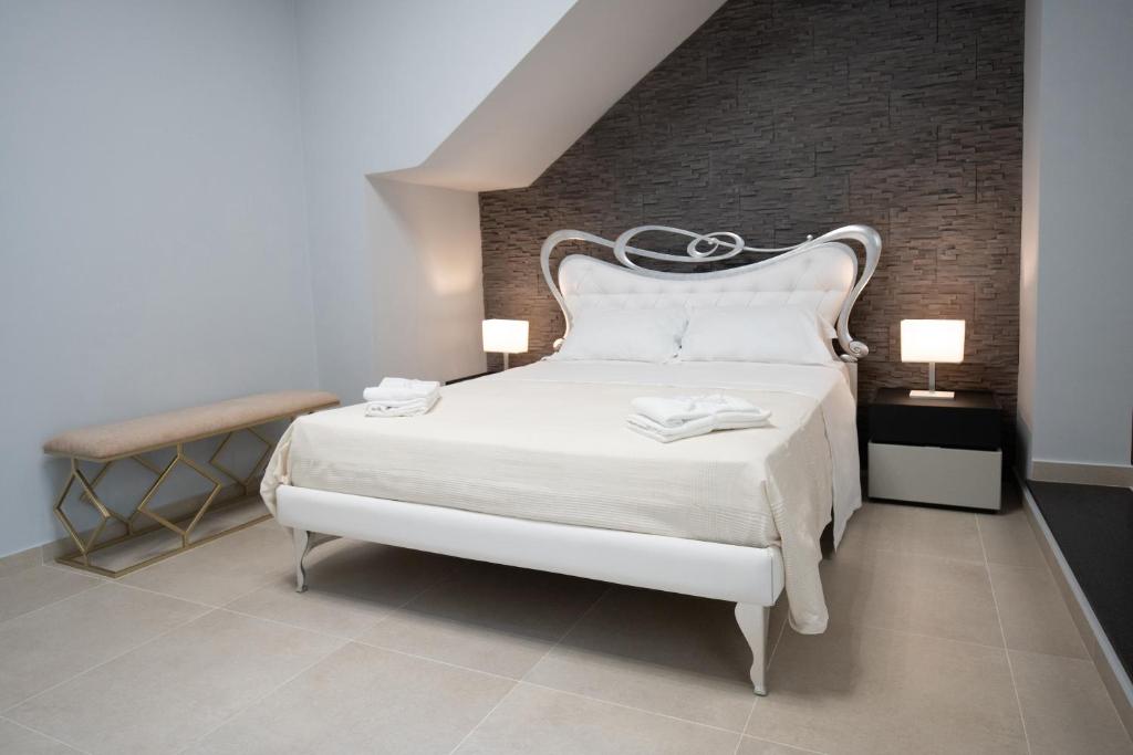 1 dormitorio con cama blanca y pared de ladrillo en iitana Luxury Apartment - Catania Fronte Mare en Catania