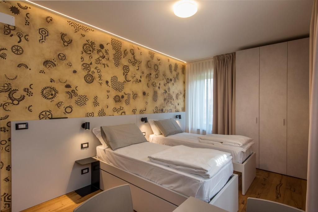 a bedroom with two beds and a wall with floral wallpaper at La Blave Rooms in Mortegliano