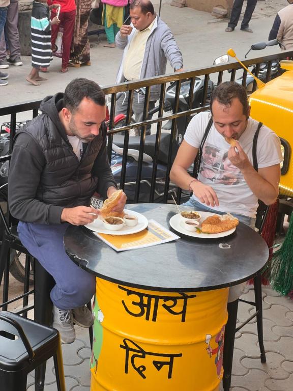 deux hommes assis à une table avec des assiettes de nourriture dans l'établissement Sugar Stars Inn, à Varanasi