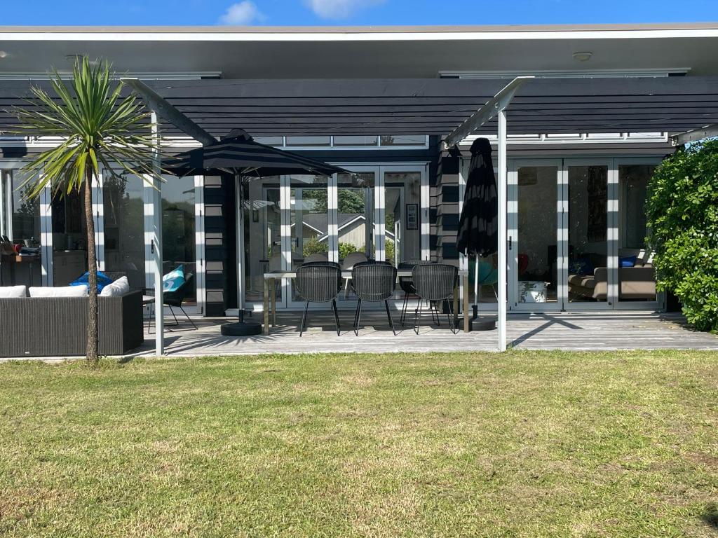 un patio con sedie e ombrelloni su una casa di Medlands Beach House a Great Barrier Island