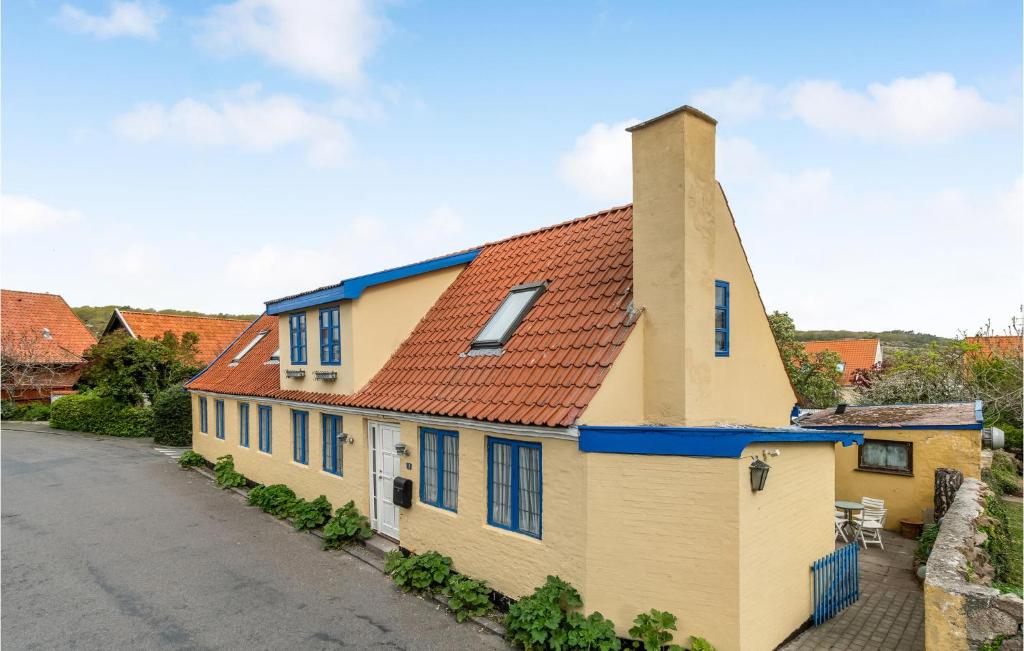 a yellow building with blue windows and a red roof at Nice Apartment In Allinge With Wifi in Allinge