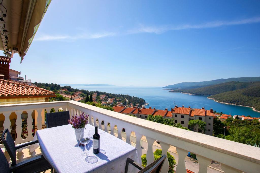 a table on a balcony with a view of the water at Greenhouse family apartments in Rabac