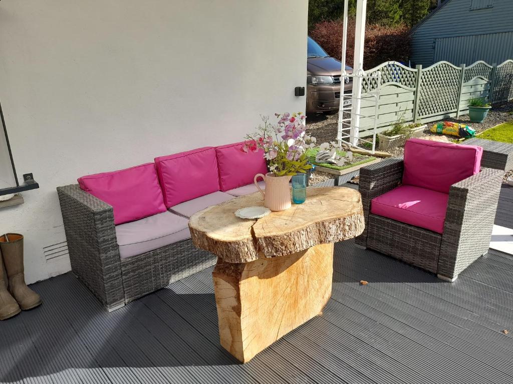 a patio with a couch and a wooden table at Pinetree Cottage, dog friendly, Holiday let, Callander Invertrossachs in Callander