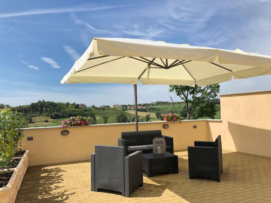 eine Terrasse mit einem Sonnenschirm, Stühlen und einem Tisch in der Unterkunft Ca' dal Bertu - Cascina in Monferrato in Rosignano Monferrato