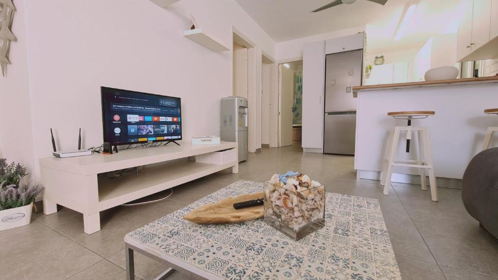 ein Wohnzimmer mit einem TV und einem Tisch in der Unterkunft STAY Kapparis Symphony in Paralimni