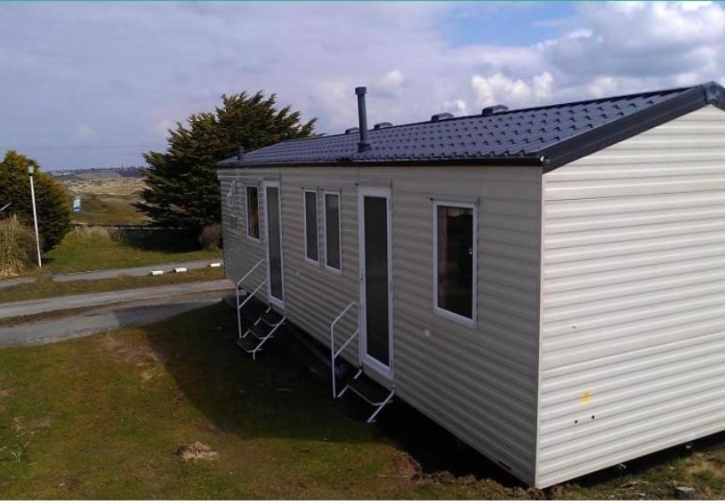 a small white building with a black roof at 6-8 berth caravan, Perran Sands Haven Holiday Park, Cornwall in Perranporth